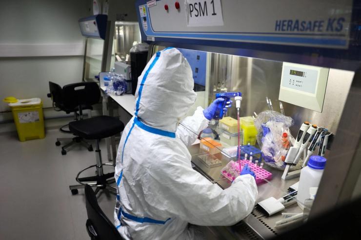 A researcher wearing protective suit works during a press visit at the Institut Pasteur.