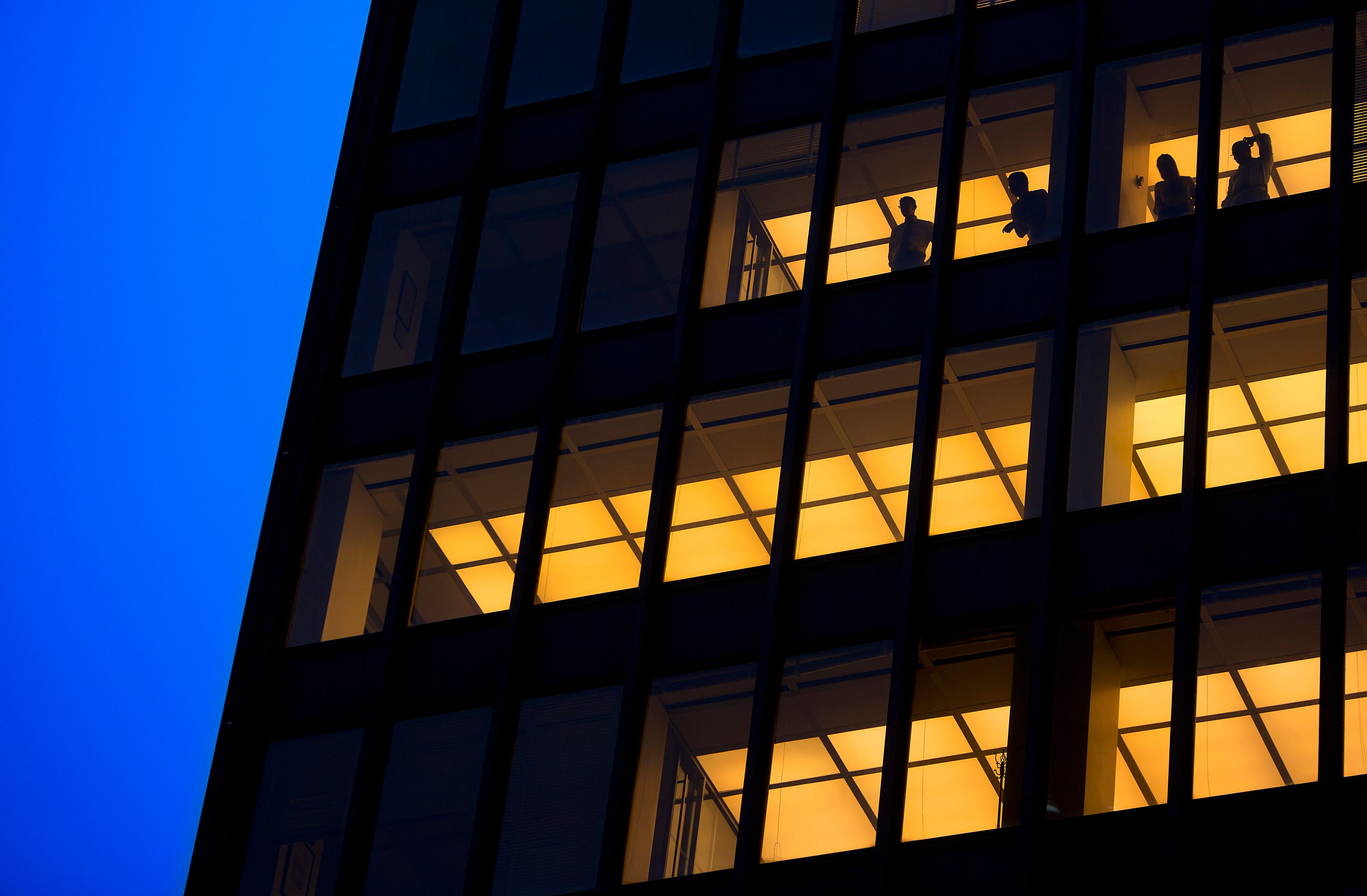 People stand in a the window of an office tower as they watch the presidential motorcade go down Park Avenue in New York.