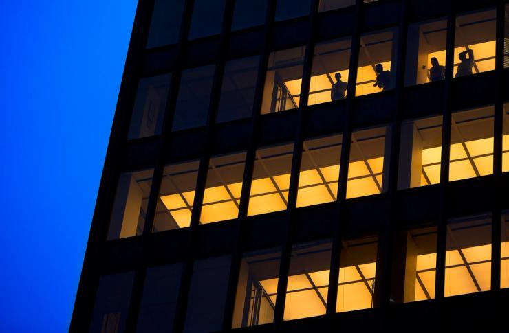 People stand in a the window of an office tower as they watch the presidential motorcade go down Park Avenue in New York.