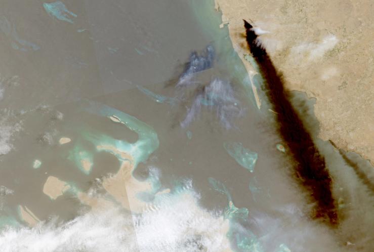A composite satellite image shows trail of smoke rising from an oil facility, in Jizan, Saudi Arabia