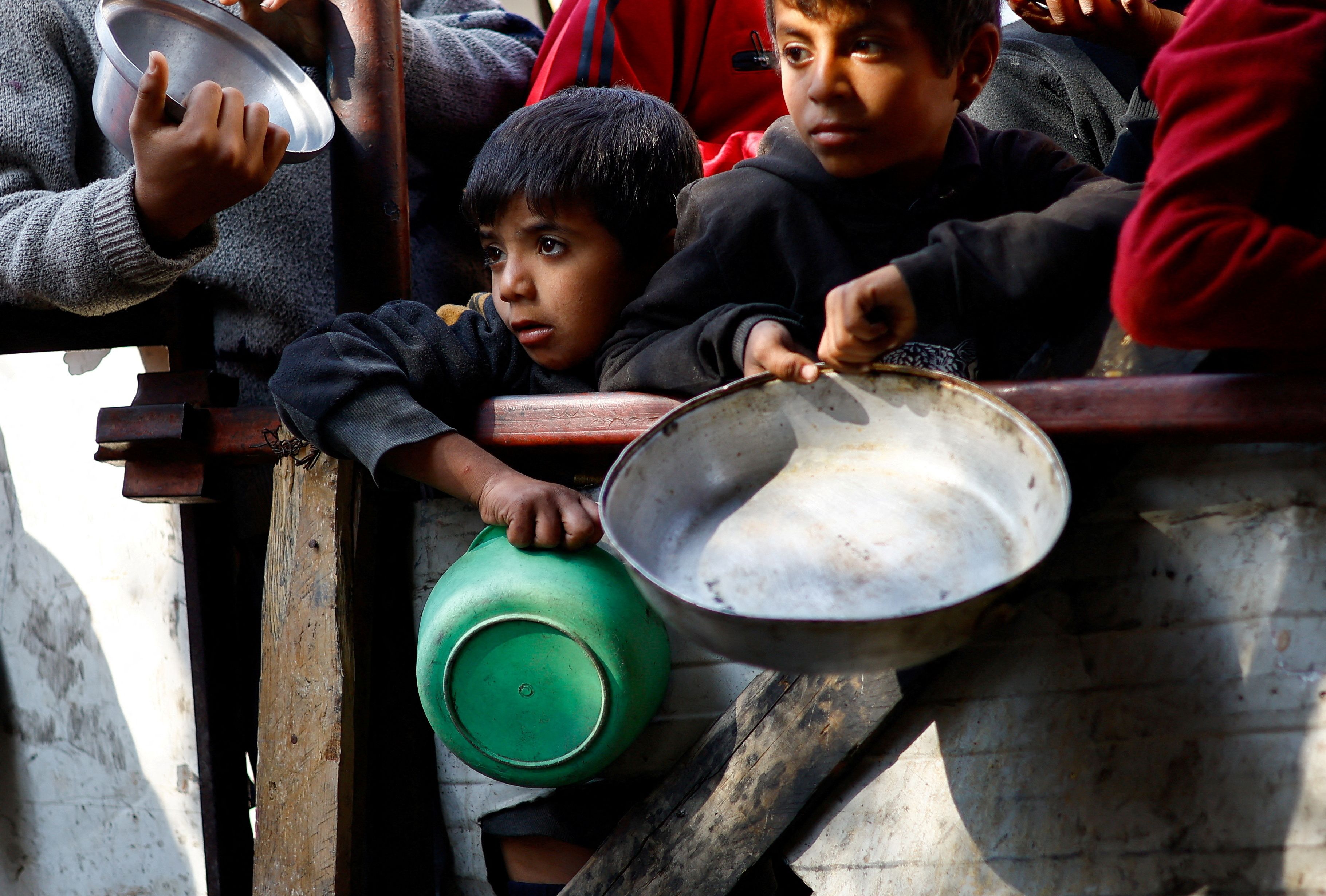 FILE PHOTO: Palestinians wait to receive food cooked by a charity kitchen amid shortages of food supplies, amid the ongoing conflict between Israel and the Palestinian Islamist group Hamas, in Rafah in the southern Gaza Strip, January 16, 2024. REUTERS/Ibraheem Abu Mustafa/File Photo