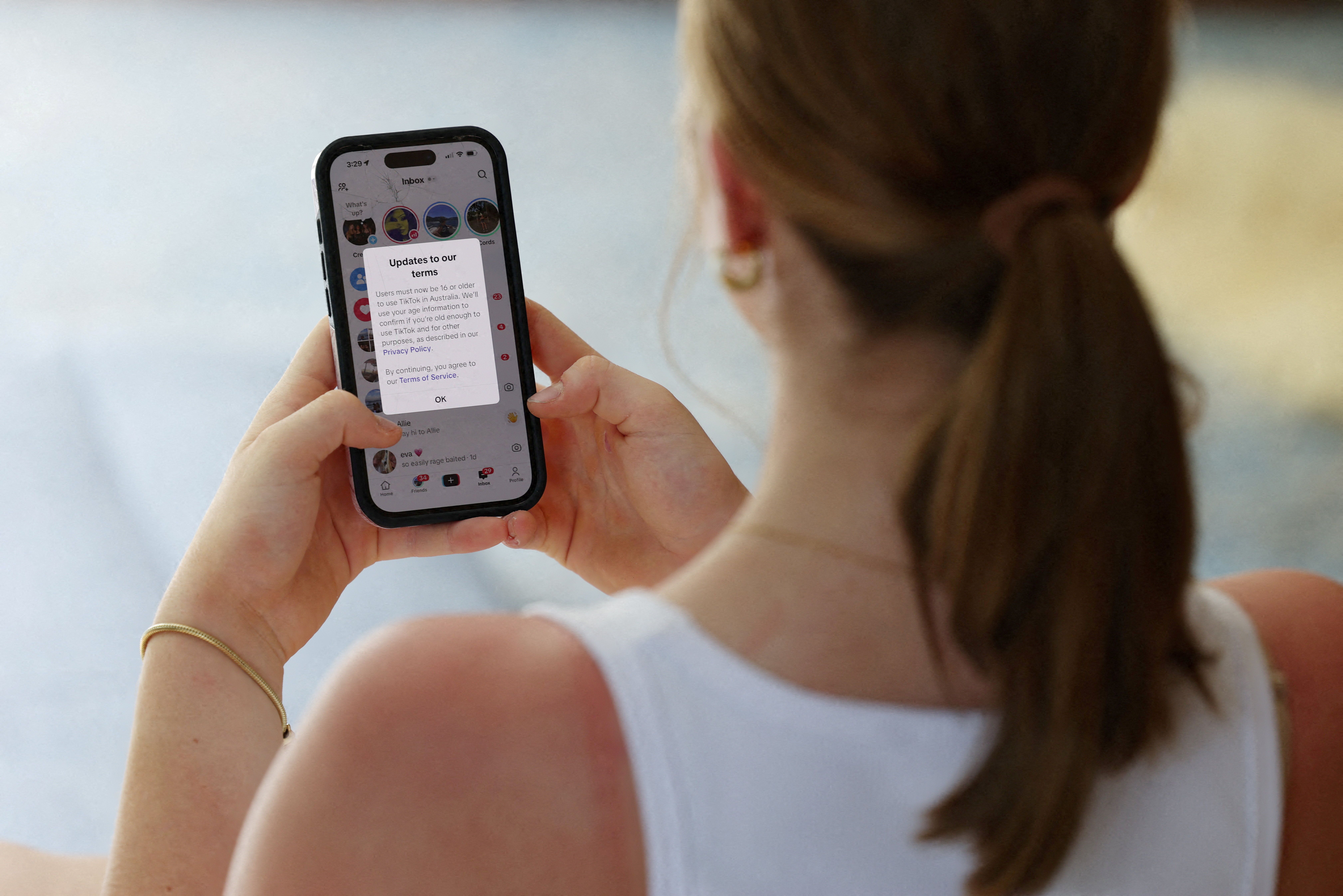 Teenager poses holding a mobile phone displaying a message from TikTok as law banning social media for users under 16 in Australia takes effect, in Sydney, Australia