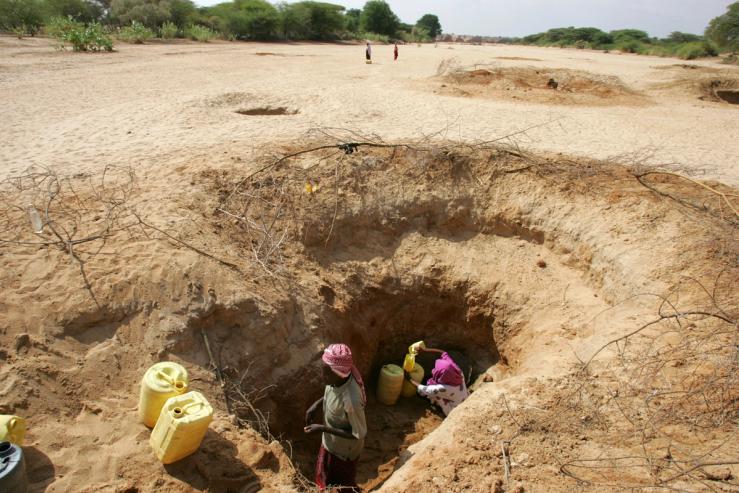 An elderly Kenyan man fetches water at a dry river bed in Kenya.