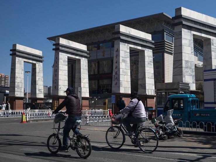 Flagship People ride bicycles near the entrance to Inner Mongolia University of Science and Technology in Baotou