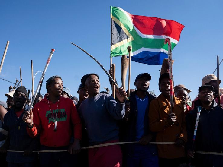 Demonstrators carry sticks and a flag during a protest calling for the deportation of undocumented immigrants.