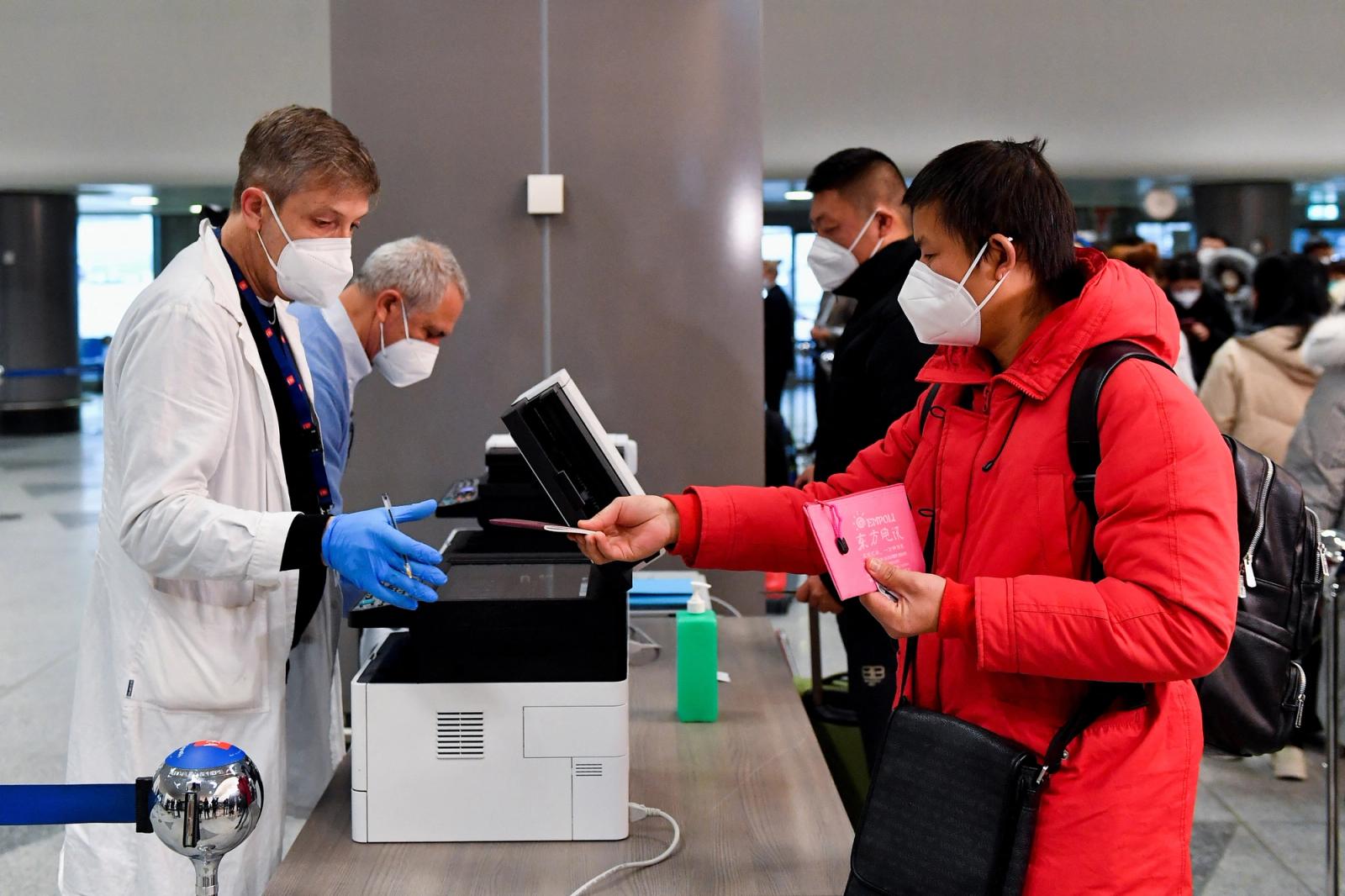 A passenger gives his passport to a worker, after Italy has ordered coronavirus disease (COVID-19) antigen swabs and virus sequencing for all travellers coming from China, where cases are surging, at the Malpensa Airport in Milan.