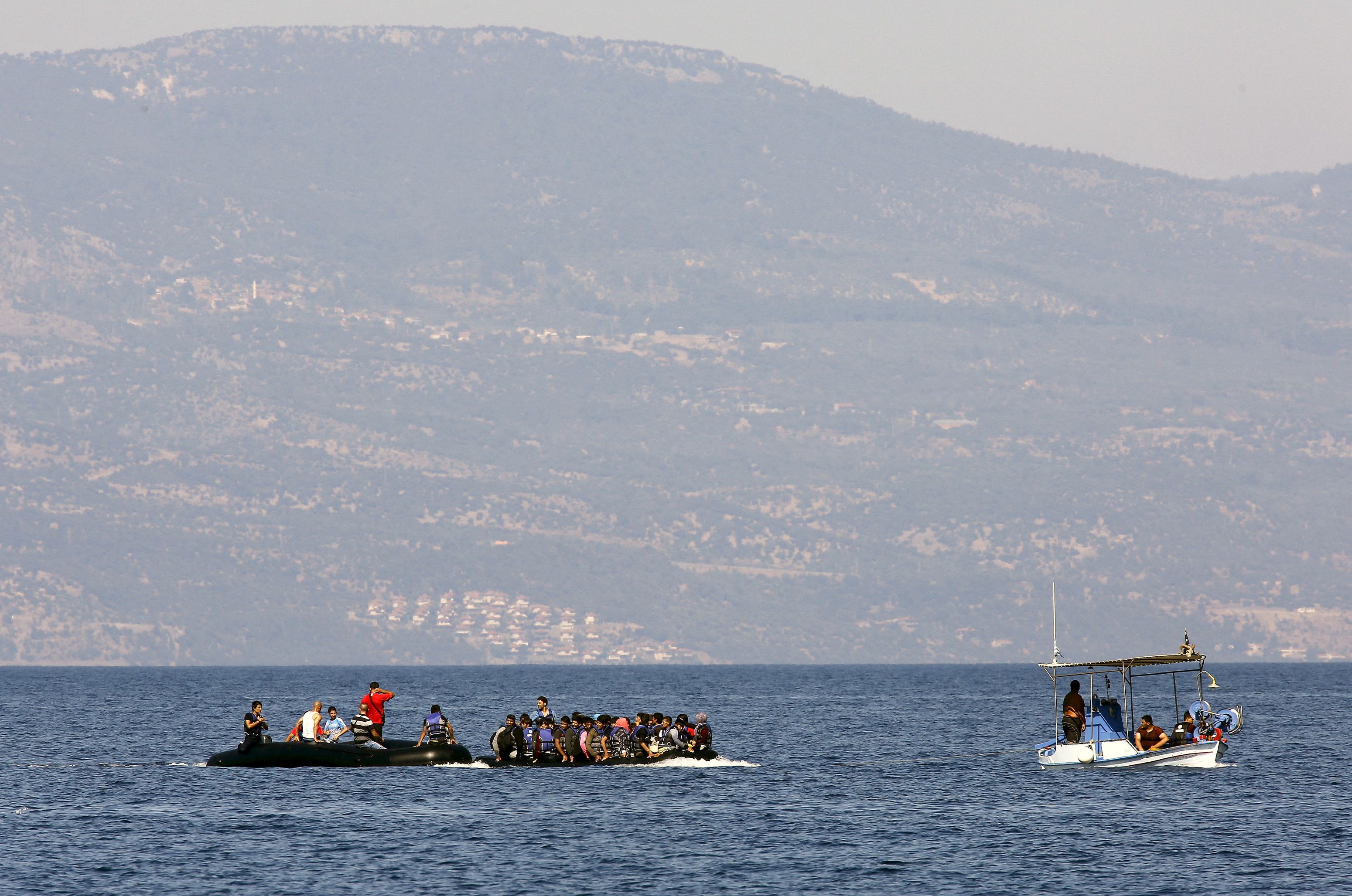 Two dinghies with Syrian refugees are towed by a Greek fishing boat at a beach on the Greek island of Lesbos.