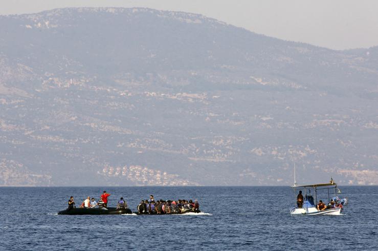 Two dinghies with Syrian refugees are towed by a Greek fishing boat at a beach on the Greek island of Lesbos.