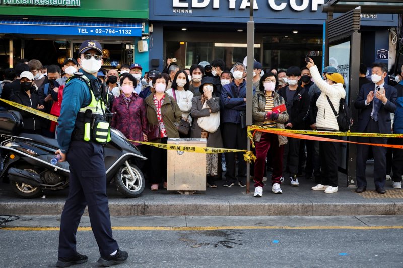 People look on as a policeman patrols the scene of the stampede in Seoul, South Korea.
