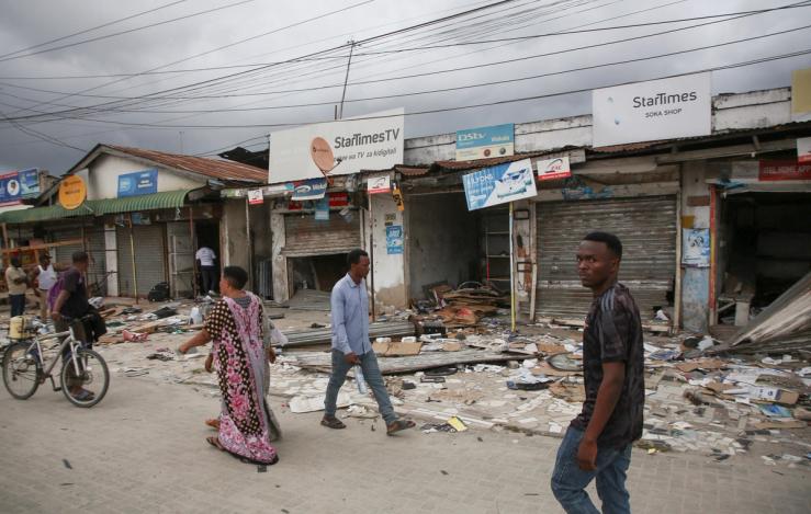 People walk past debris outside electronic stores looted during protests.