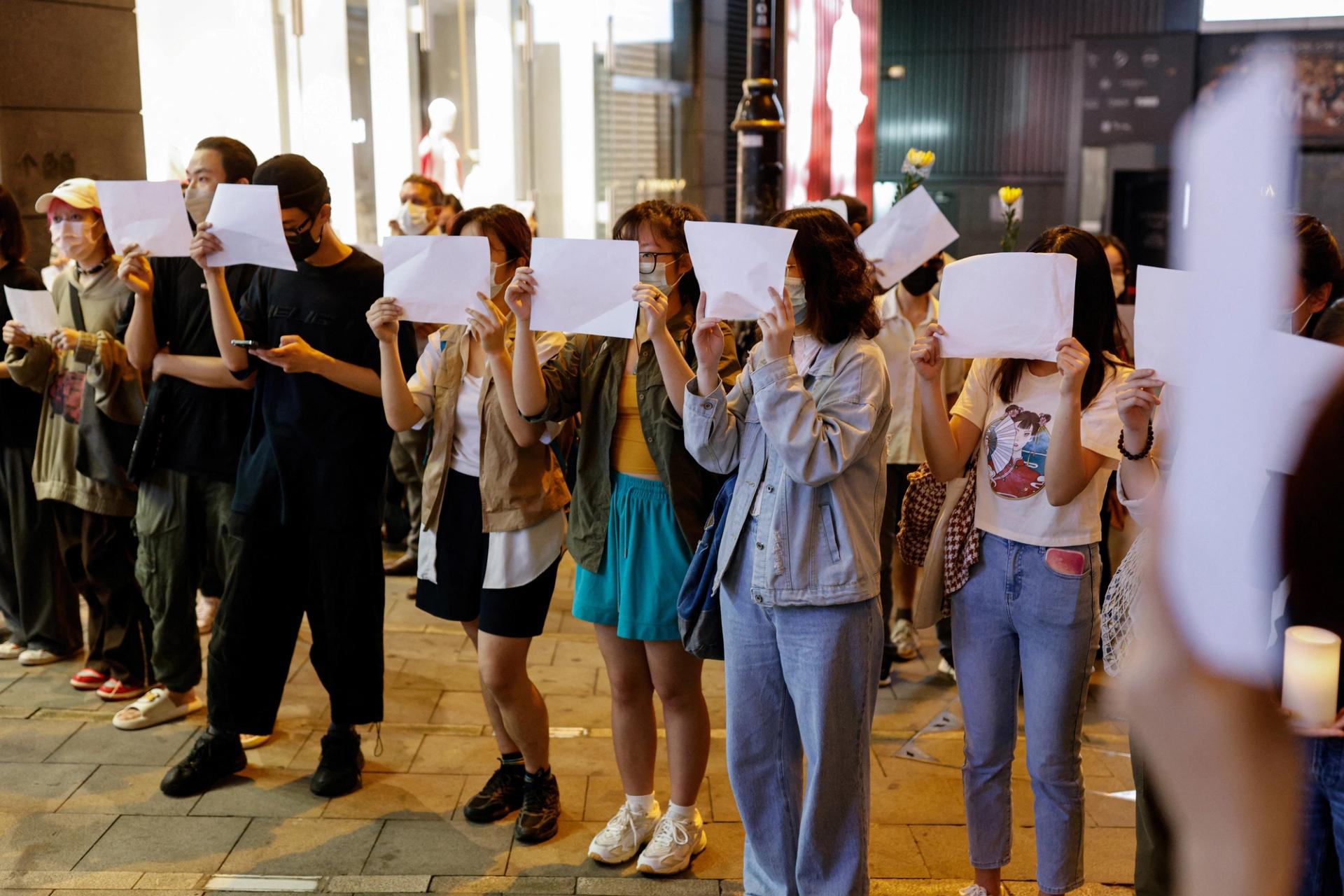 People hold sheets of paper in protest over coronavirus disease (COVID-19) restrictions in mainland China, during a commemoration of the victims of a fire in Urumqi