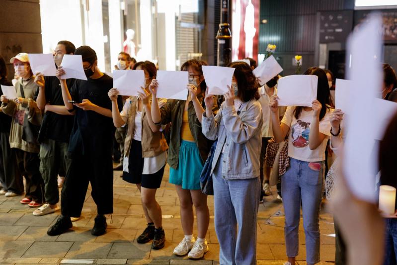 People hold sheets of paper in protest over coronavirus disease (COVID-19) restrictions in mainland China, during a commemoration of the victims of a fire in Urumqi