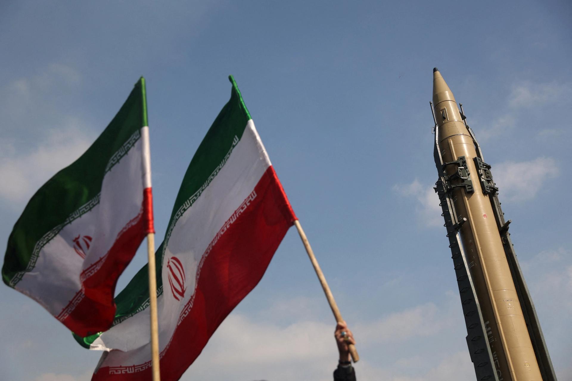 People wave flags next to an Iranian missile on display during the 46th anniversary of the Islamic Revolution in Tehran, Iran, February 10, 2025.