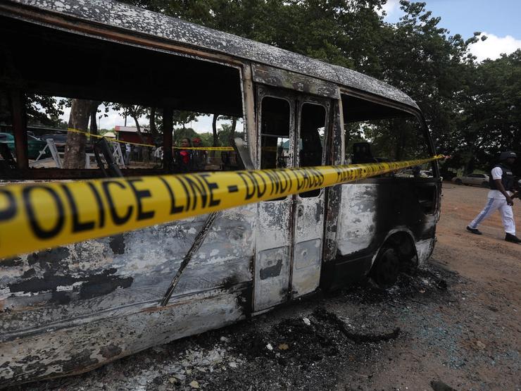 A police officer walks beside a burnt prison vehicle in Abuja, Nigeria on July 6, 2022, after suspected Boko Haram attack.