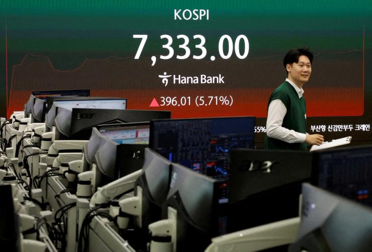 A currency dealer looks on as an electronic board displays the Korea Composite Stock Price Index (KOSPI), at the dealing room of a bank, as the benchmark KOSPI index opened above the 7,000 mark in Seoul, South Korea