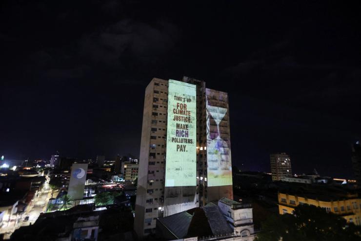 A message is projected on a building during a demonstration by OXFAM at COP30.