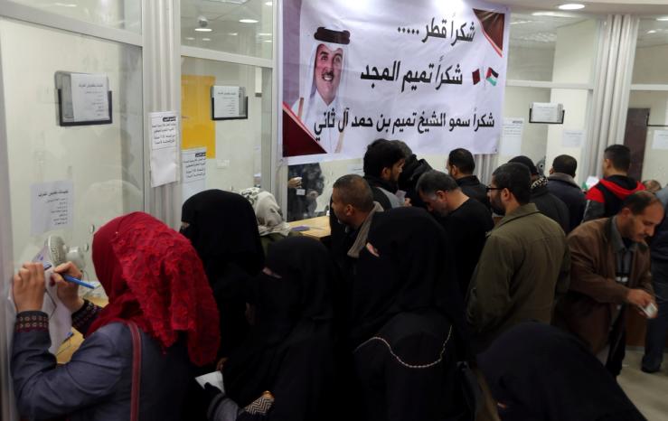 Palestinian Hamas-hired civil servants wait to receive their salaries paid by Qatar as a banner showing a picture of Qatar’s Sheikh Tamim bin Hamad Al Thani is seen, in Khan Younis in the southern Gaza Strip December 7, 2018.