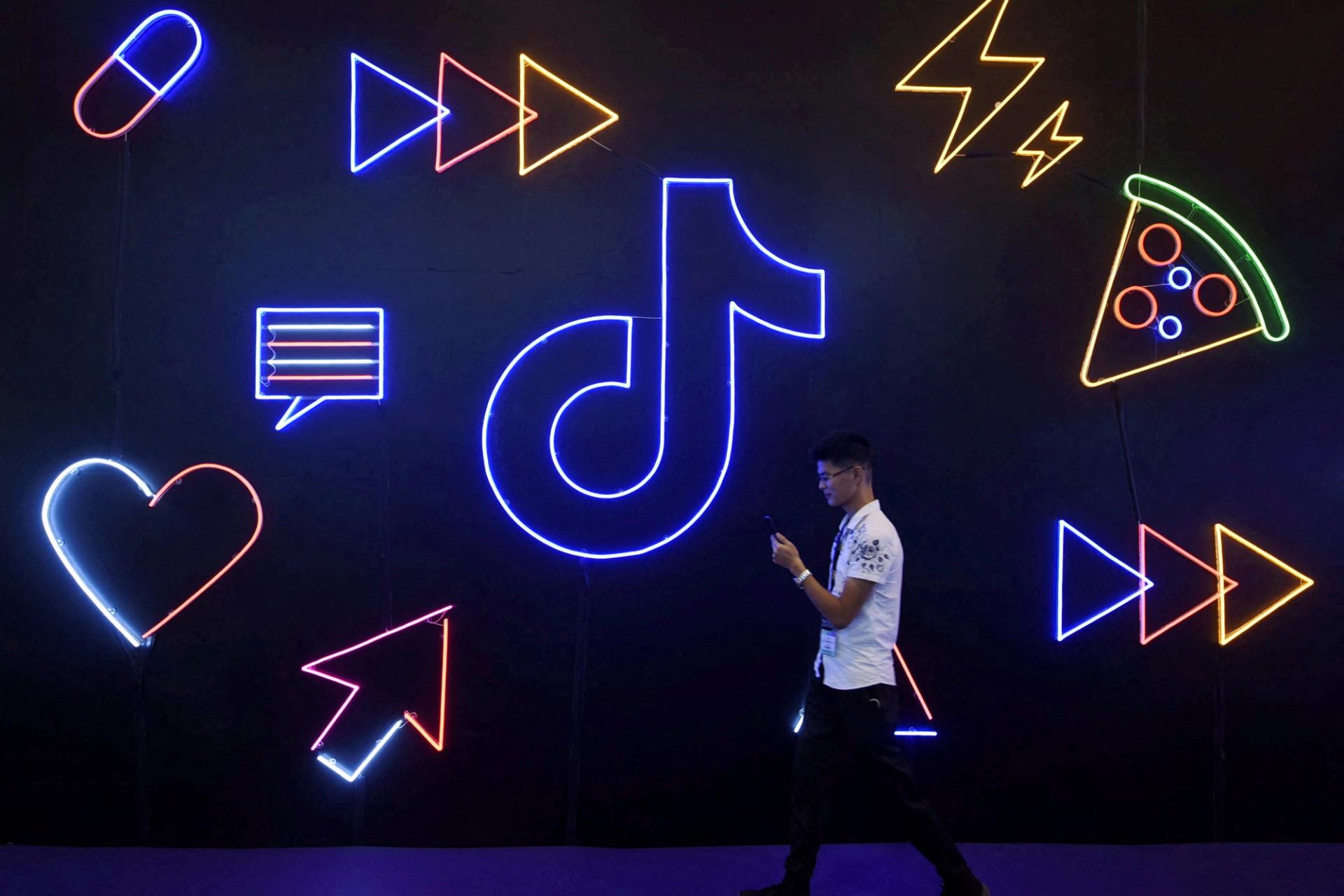 A man holding a phone walks past a sign of Chinese company ByteDance’s app TikTok, known locally as Douyin, at the International Artificial Products Expo in Hangzhou