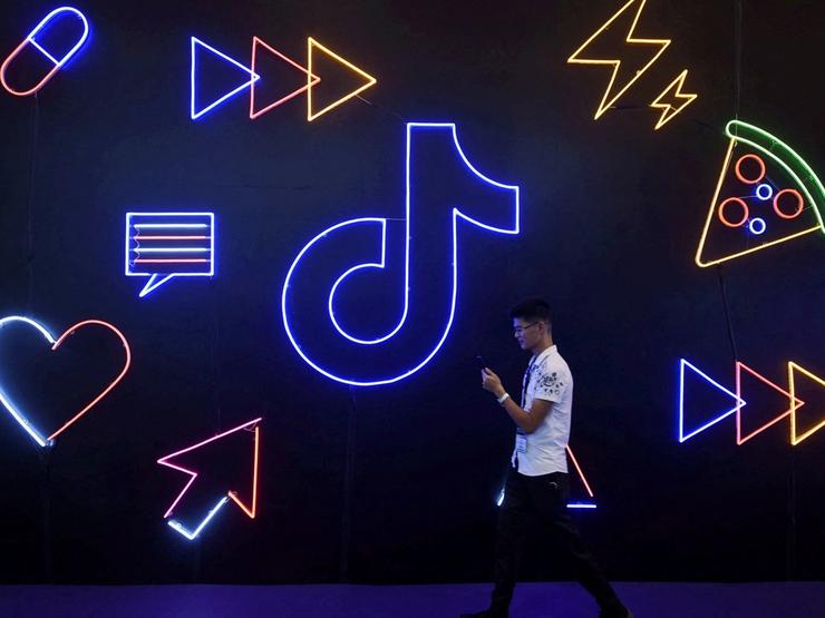 A man holding a phone walks past a sign of Chinese company ByteDance’s app TikTok, known locally as Douyin, at the International Artificial Products Expo in Hangzhou