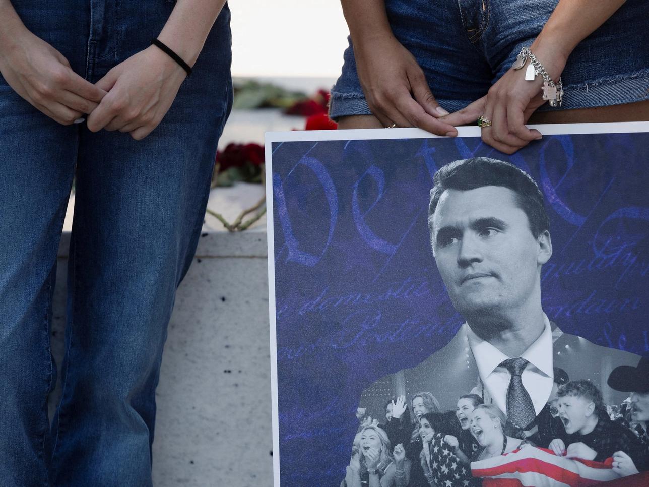 People hold a poster of Charlie Kirk