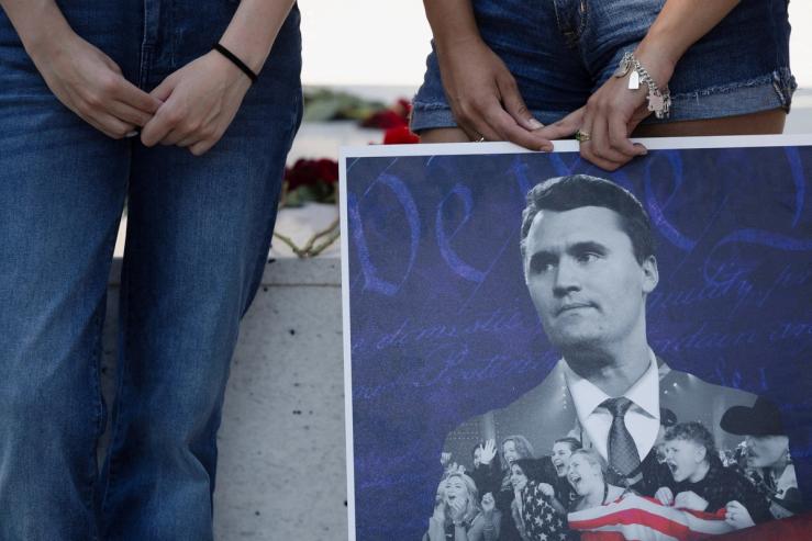 People hold a poster of Charlie Kirk