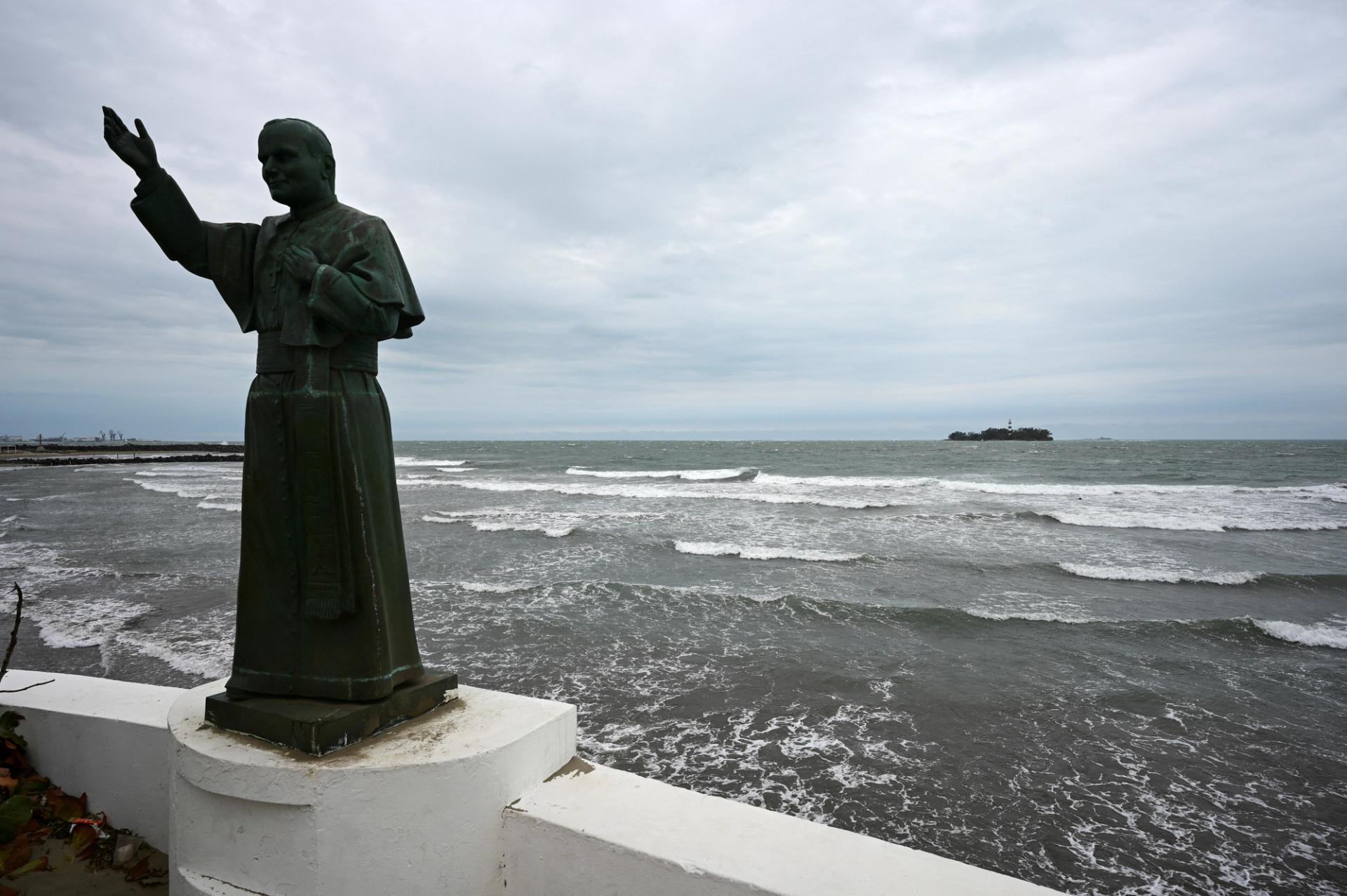 A statue of pope John Paul II is seen at a jetty as waves crash on the shore of the Gulf of Mexico.