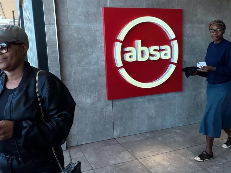 A person walks past a logo of South African retail bank Absa.