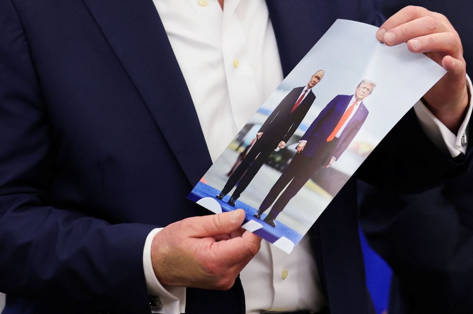 Trump holding up a photo of him and Putin. 