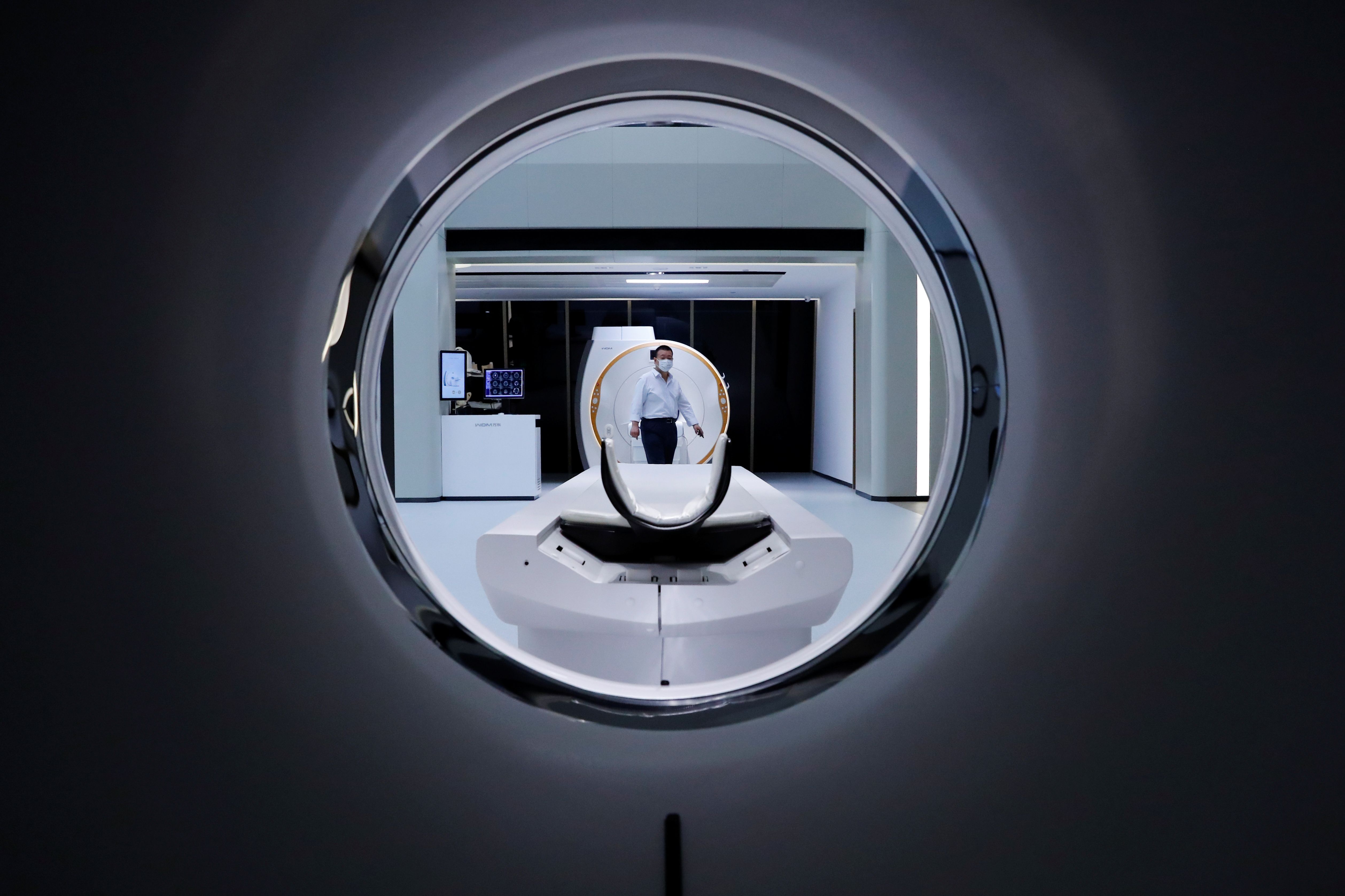 A man is seen through a CT scanner at the showroom of the medical imaging equipment maker Beijing Wandong WDM Medical Technology Co. during a government organised tour of the facilit.