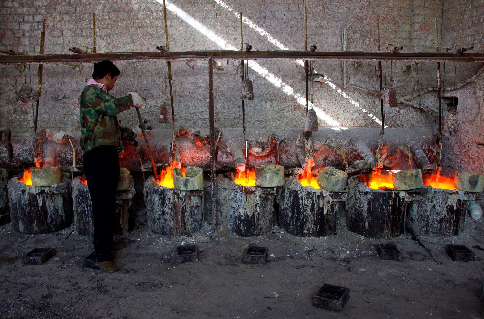 A worker at the Jinyuan Company’s smelting workshop stokes the pots containing the rare earth metal Lanthanum near the town of Damao, located in China’s Inner Mongolia Autonomous Region 