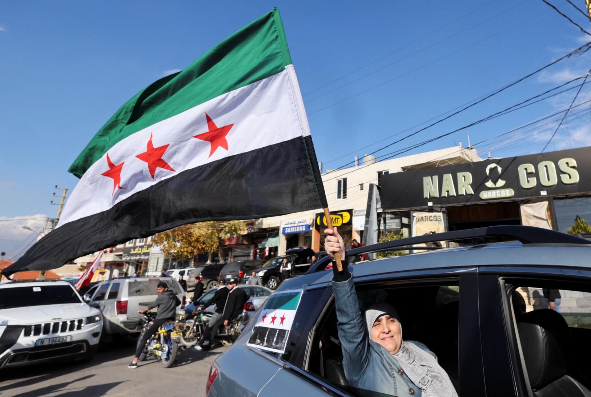 A woman waves a Syrian opposition flag from a vehicle at Masnaa Border Crossing.