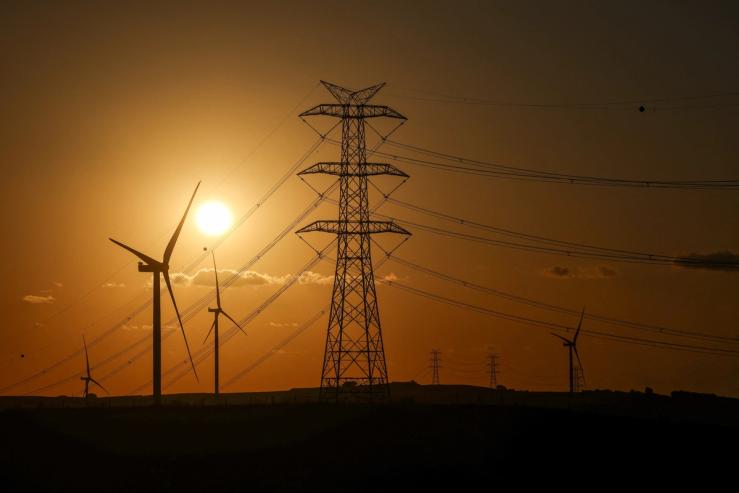 The sun sets behind wind turbines