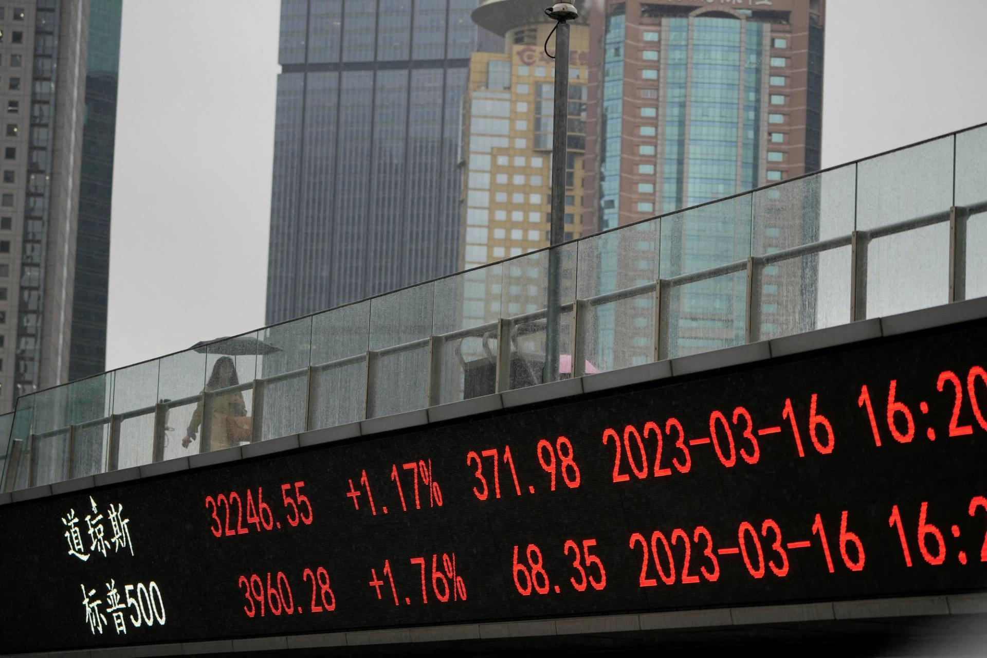 An electric board shows stock indices, written in red, at the Lujiazui financial district in Shanghai.