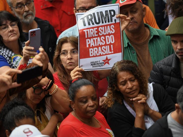 A protester holds a sign that reads “Trump, Get Your Paws Off Brazil.”
