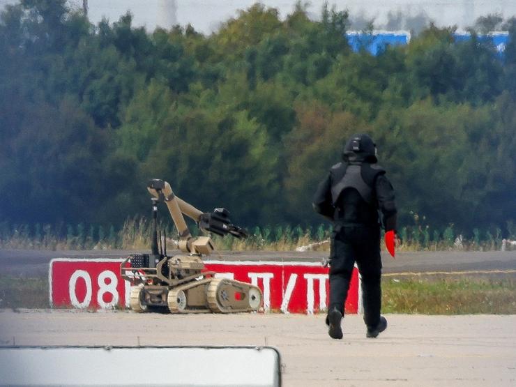 A police officer walks towards an explosive-disarming robot at Leipzig /Halle Airport.