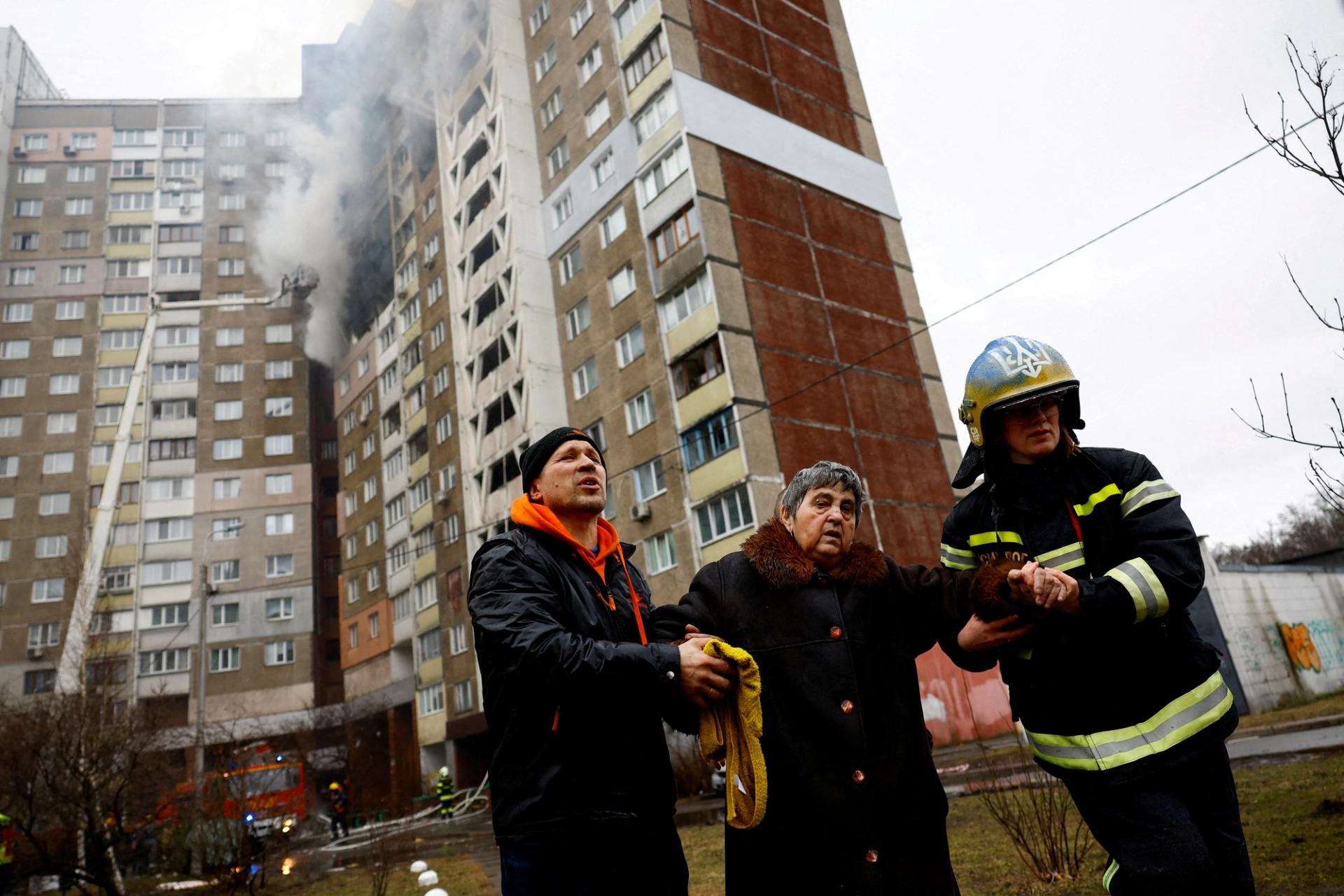 Firefighters help a woman from a building damaged during a Russian missile strike, amid Russia's attack on Ukraine, in Kyiv, Ukraine February 7, 2024.