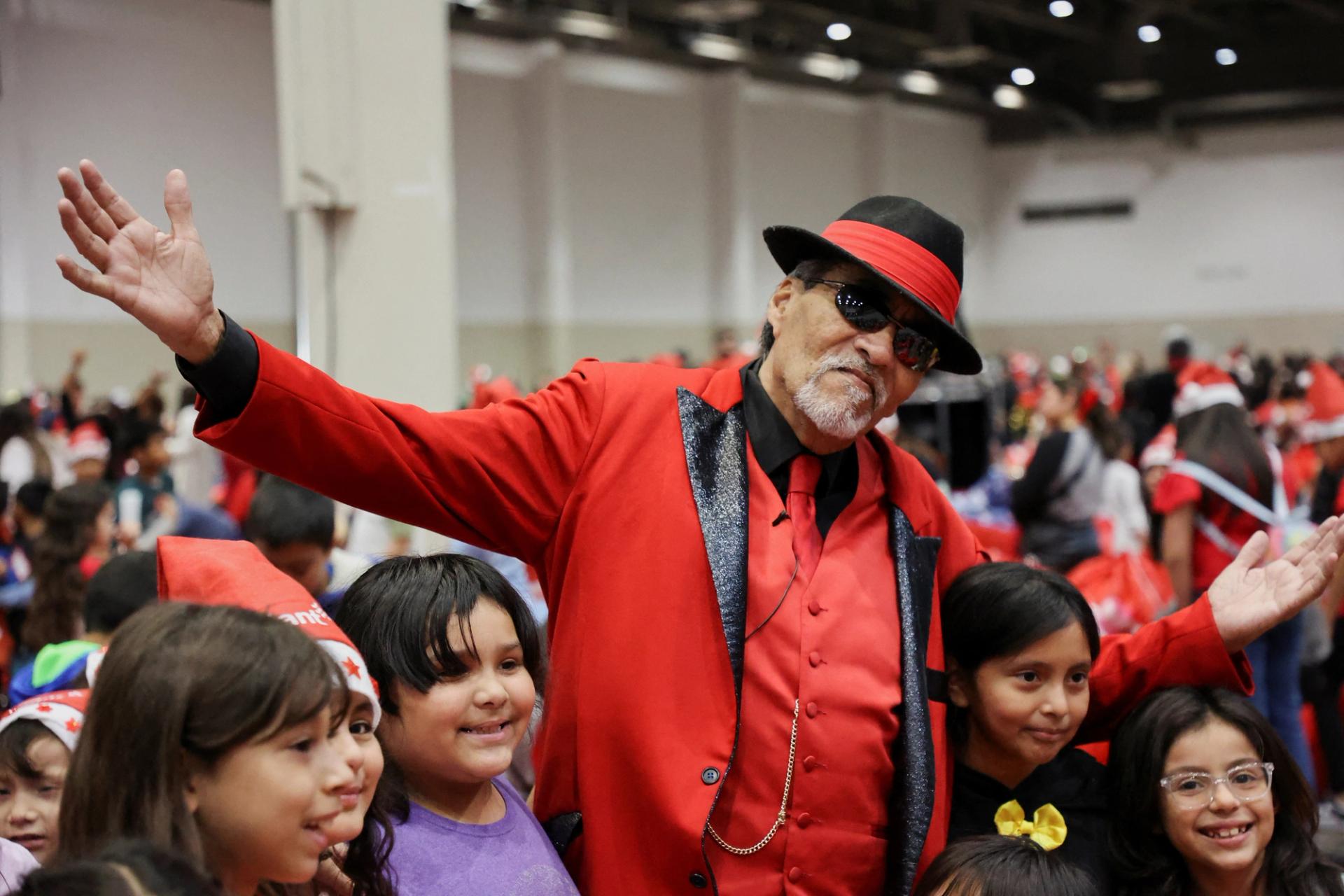 Richard Reyes, dressed as Pancho Claus, poses with children at the Navidad en el Barrio event in Houston, Texas, U.S., December 16, 2023.