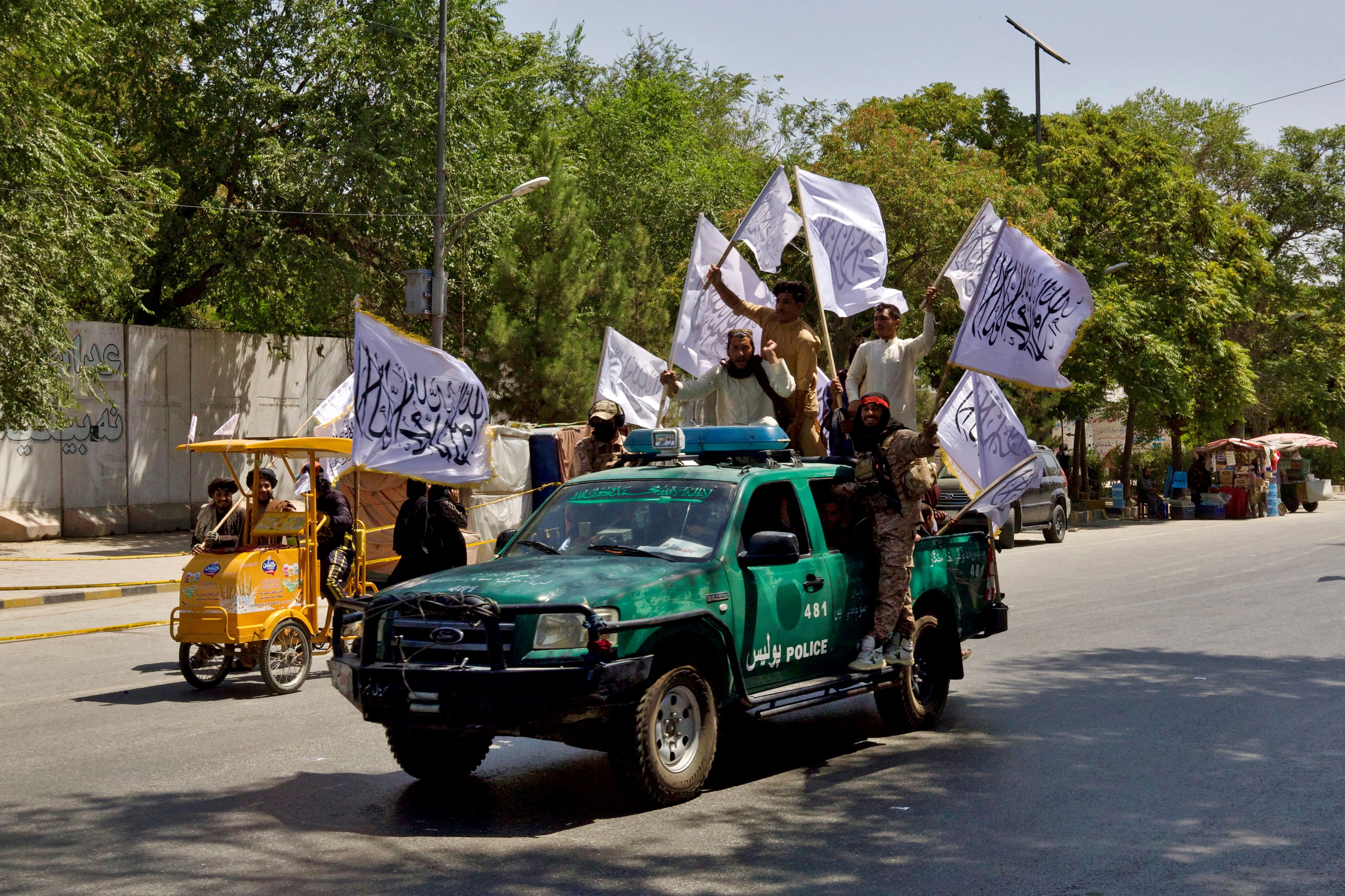Members of the Taliban carrying flags participate in a rally to mark the third anniversary of the fall of Kabul, in 2024.