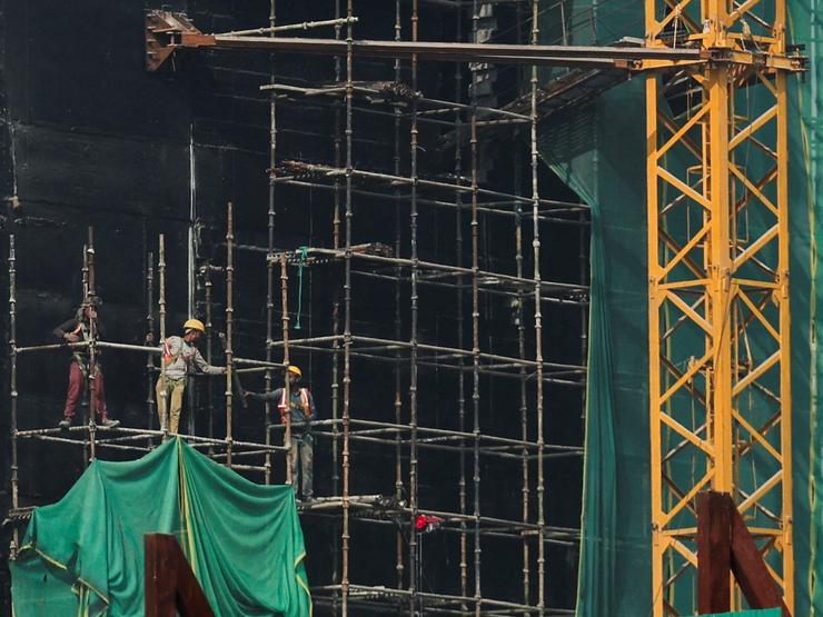Laborers work on a building near Kartavya Path in New Delhi, India