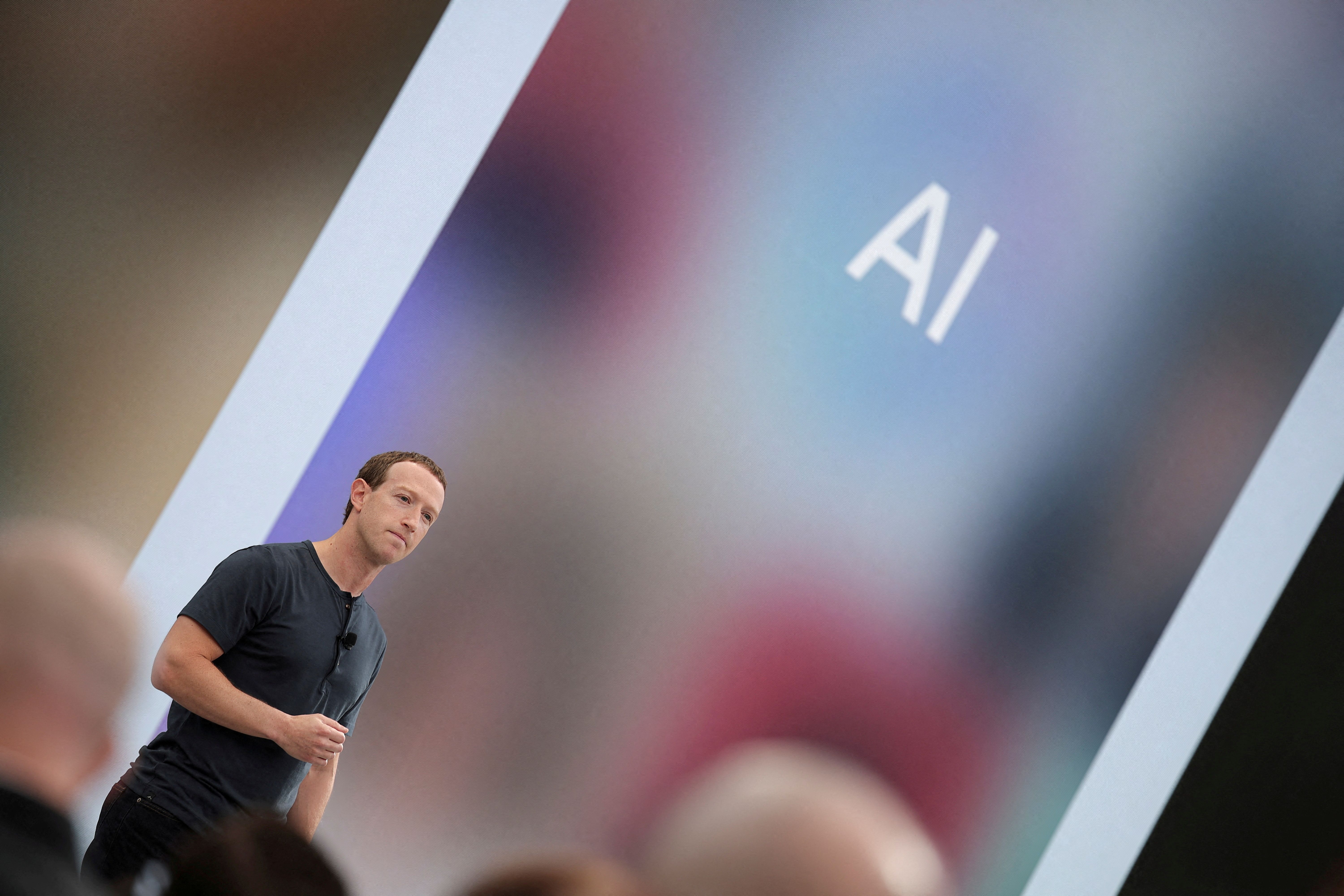 Meta CEO Mark Zuckerberg delivers a speech, as the letters AI for artificial intelligence appear on screen.