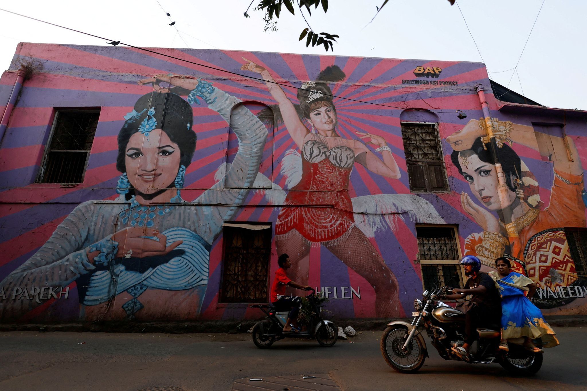  People ride past murals of Bollywood actresses in Mumbai.