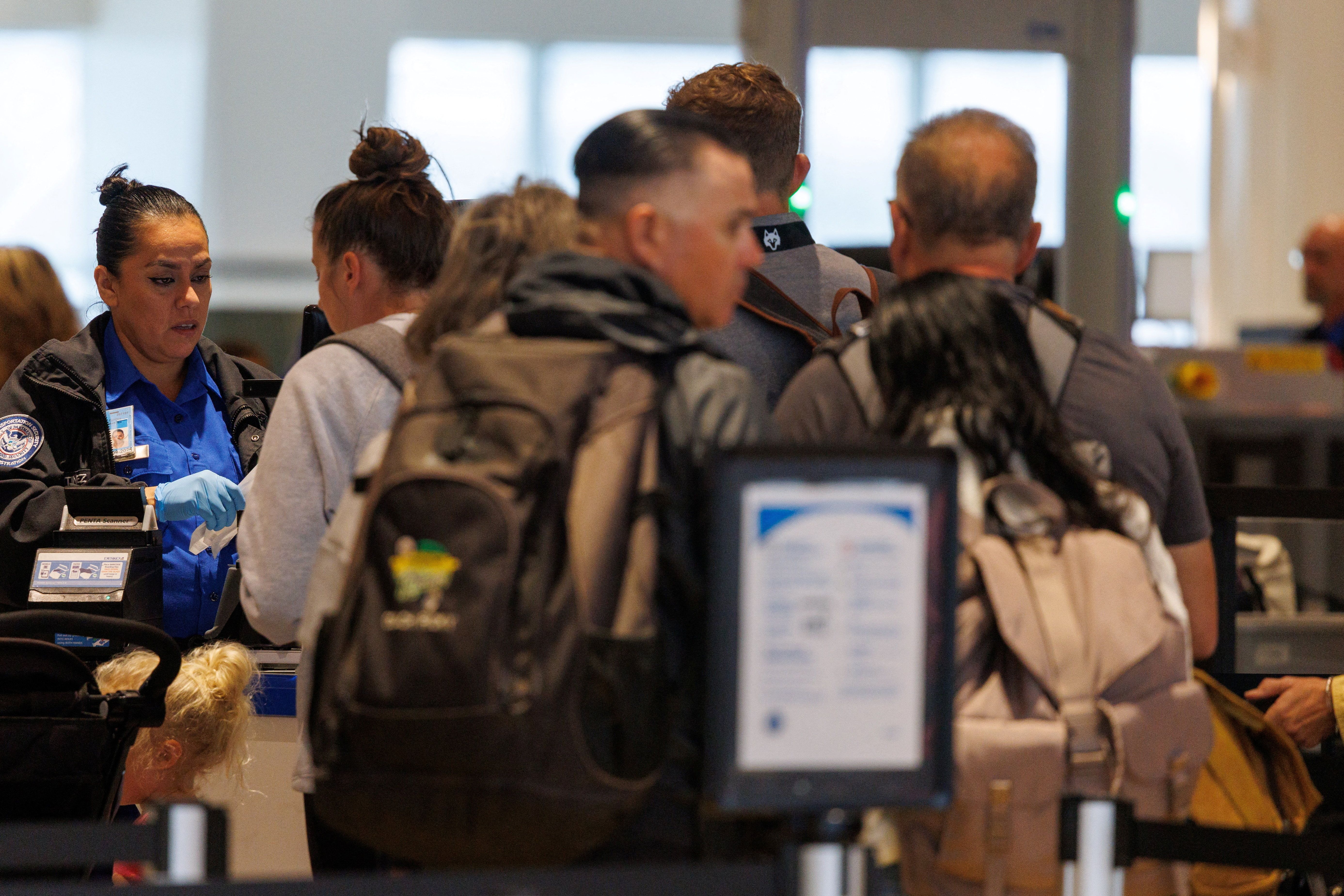 A TSA agent checks travelers at San Diego International Airport after U.S. Department of Transportation, due to the ongoing government shutdown, imposed a 10% cutback on flight capacity at selected airports that include the country’s busiest one-runway airport in San Diego, California, U.S., November 7, 2025. 