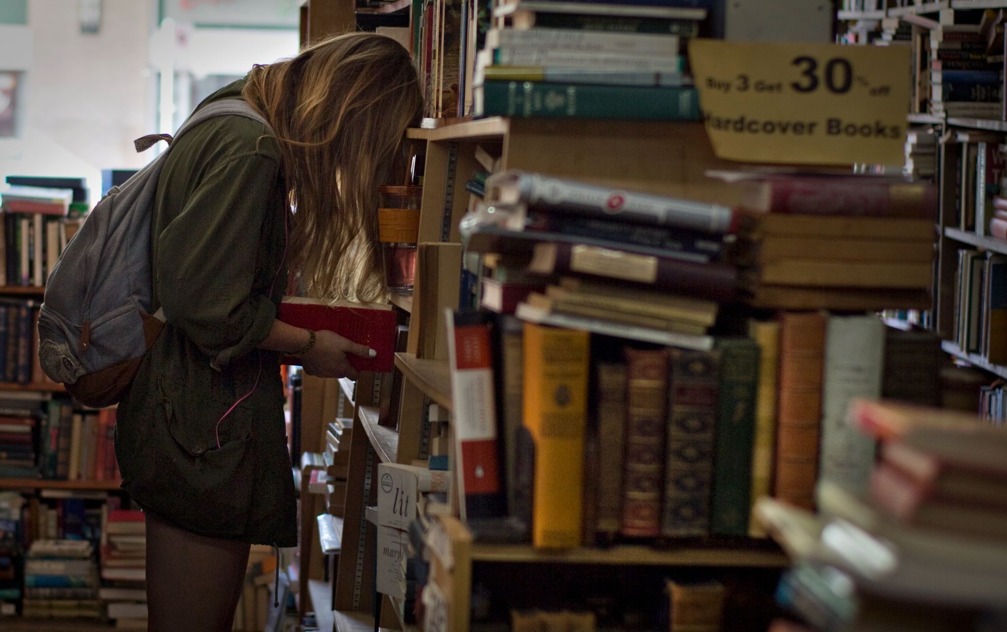 A young woman with her head in a book, in a store for used books