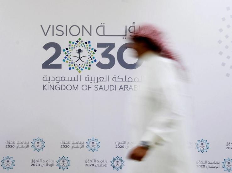 A Saudi man walks past the logo of Vision 2030 after a news conference in Jeddah.
