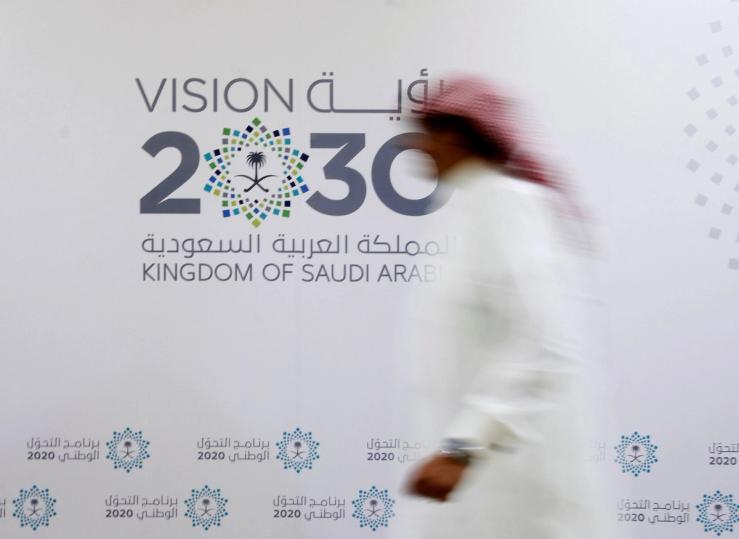 A Saudi man walks past the logo of Vision 2030 after a news conference in Jeddah.