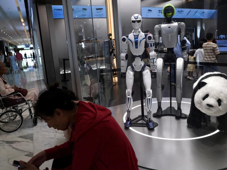 People rest near Unitree’s G1 and R1 humanoid robots on display at a Unitree store in Beijing, China
