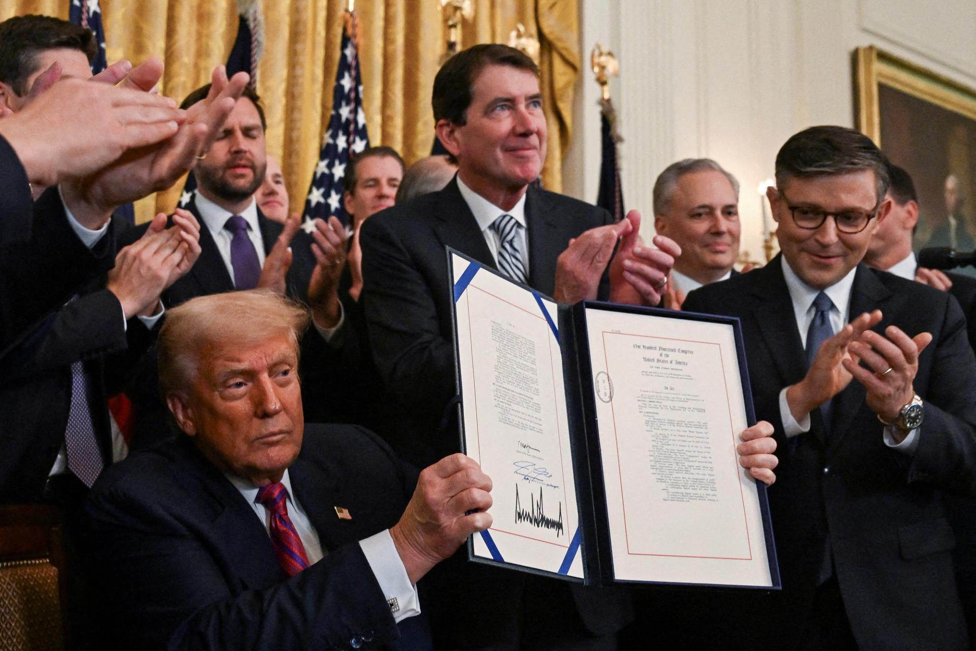 Donald Trump holds the signed act that establishes a regulatory framework for stablecoin cryptocurrencies.
