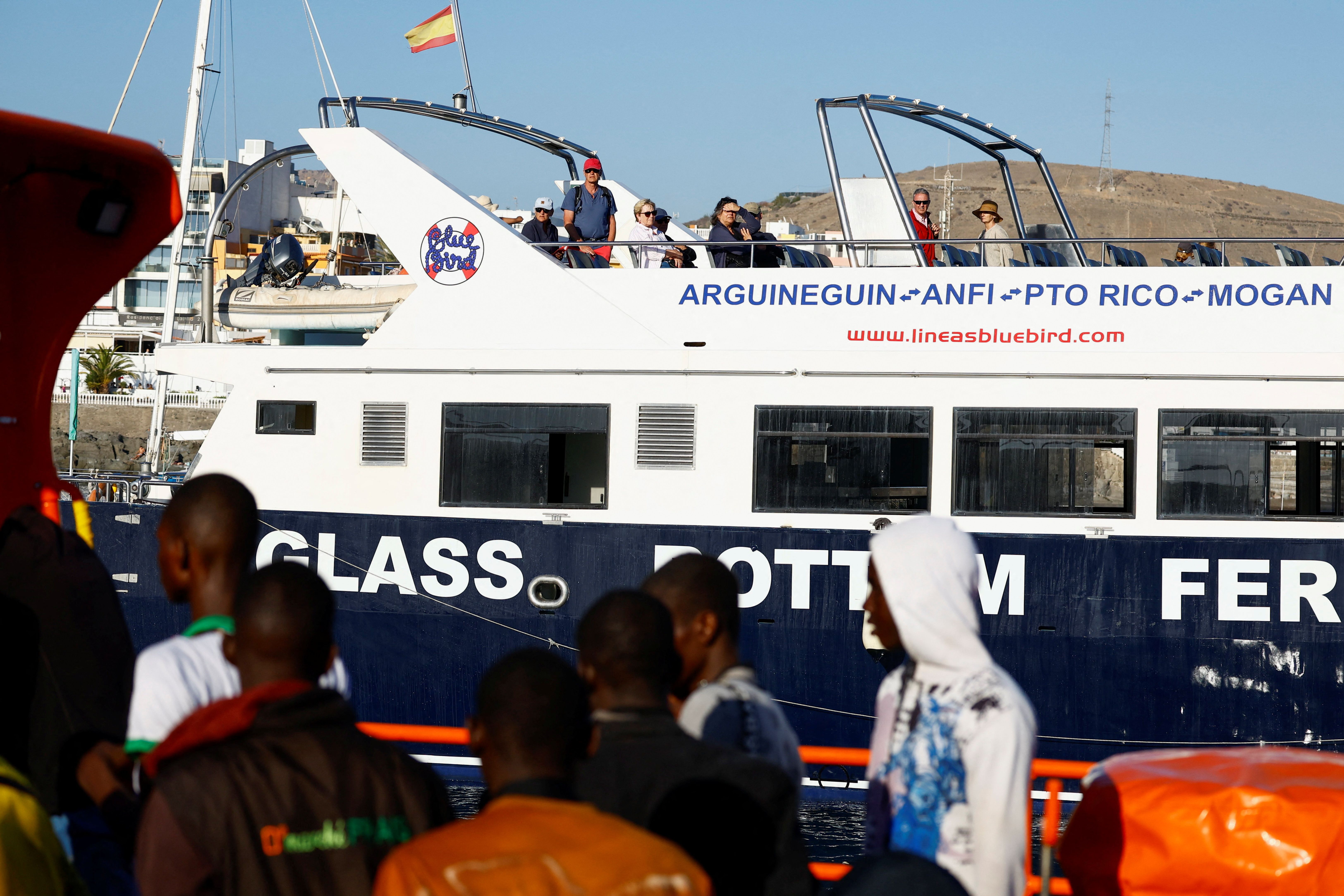 A group of migrants disembark from a Spanish Coast Guard vessel. 