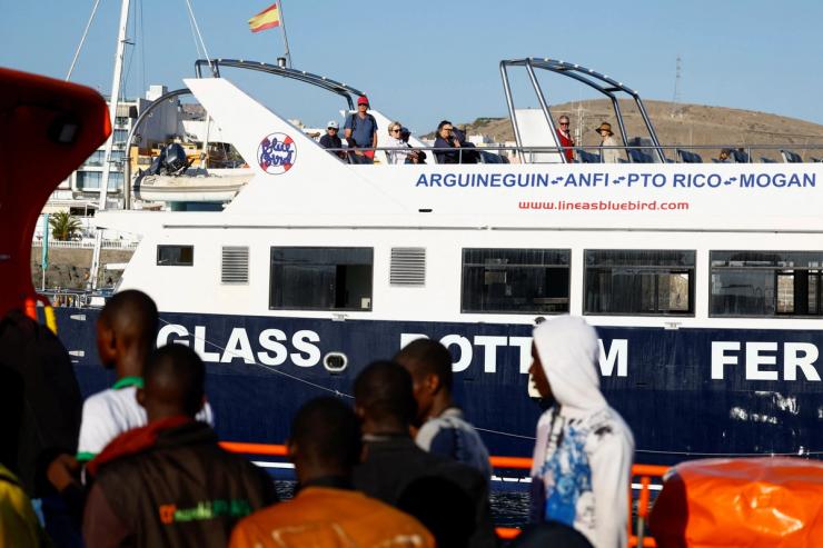 A group of migrants disembark from a Spanish Coast Guard vessel.