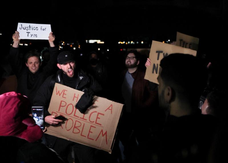 People react as they hold signs on the day of the release of a video showing police officers beating Tyre Nichols, the young Black man who was killed during a traffic stop by Memphis police officers, in downtown Memphis, Tennessee